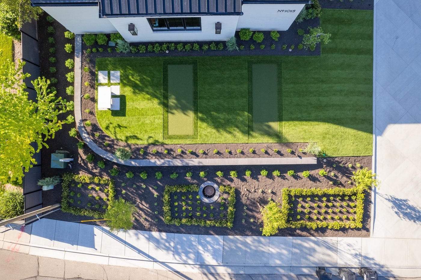 Overhead view of a designed garden with clipped parterre beds, hedging, lawn and a paver walk