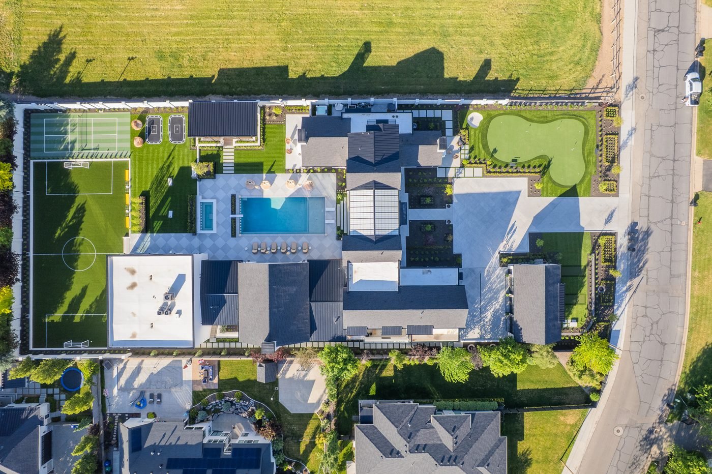 Complete outdoor environment at the Kaysville Modern Estate seen from above - pool and spa, sport court, putting green, hardscape and planting
