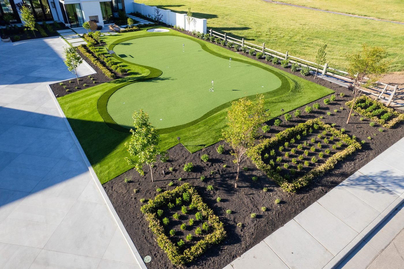 Large-format paver terrace beside a putting green and newly planted beds at a Kaysville estate