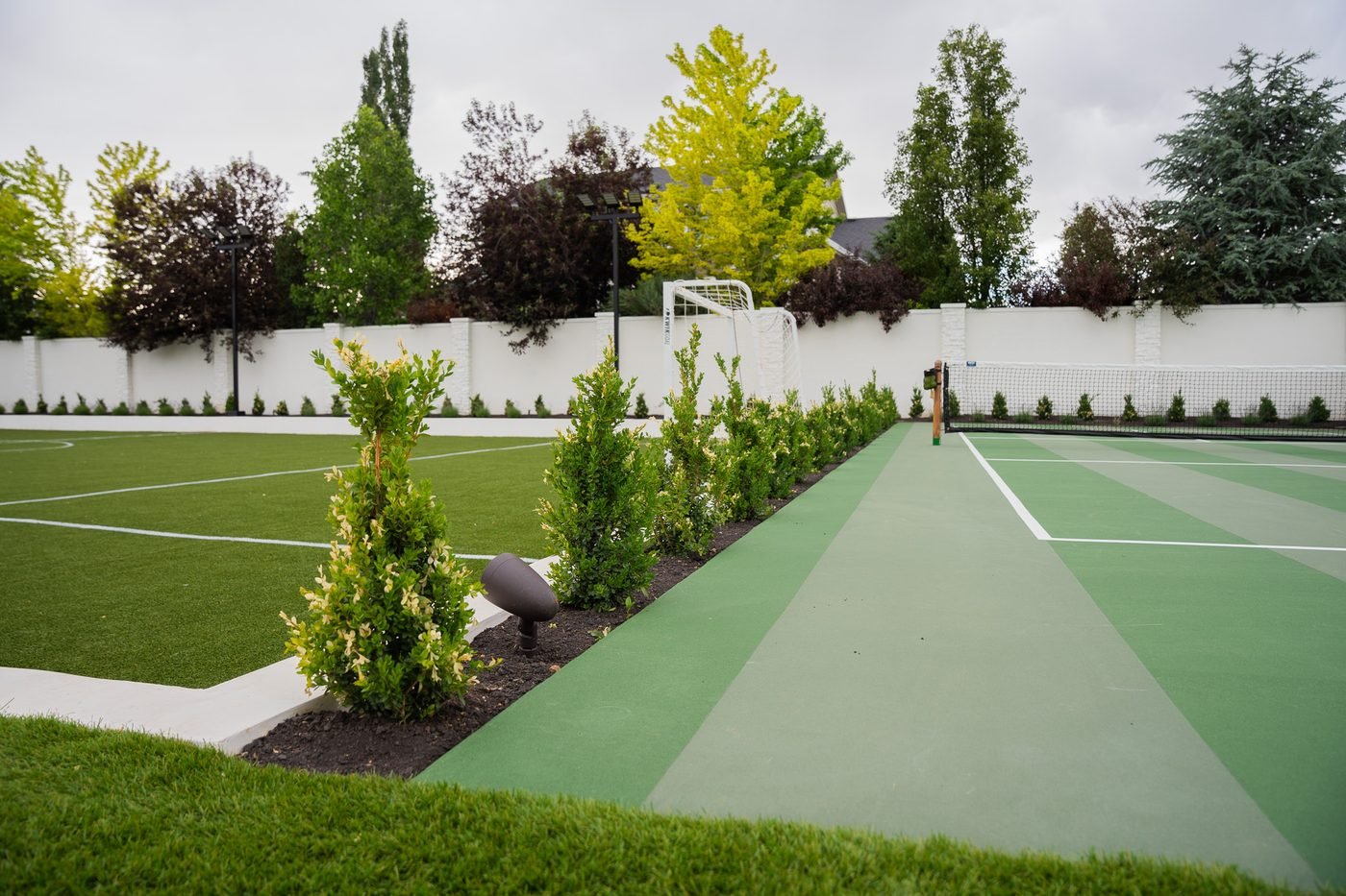 Sport court and turf field with planted beds and landscape lighting at a Kaysville estate