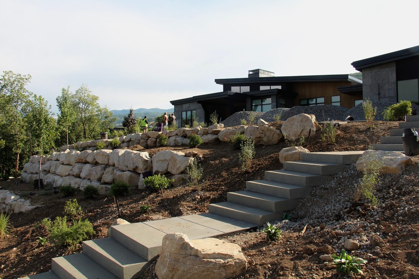 Boulder retaining walls and cast concrete steps turning a sloped lot into usable terraces