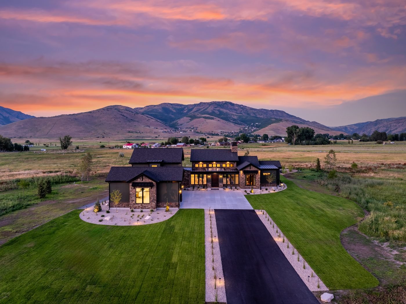 Finished property at dusk with landscape lighting on, mountains behind