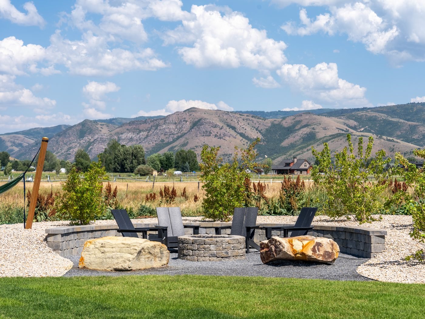 Gas fire pit with a curved block seat wall and gravel patio, looking out to the mountains