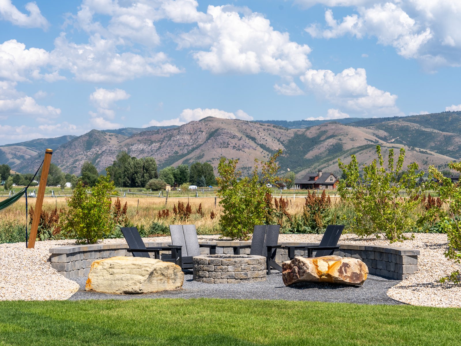 Gas fire pit with a block seat wall and gravel patio overlooking the mountains in Huntsville, Utah